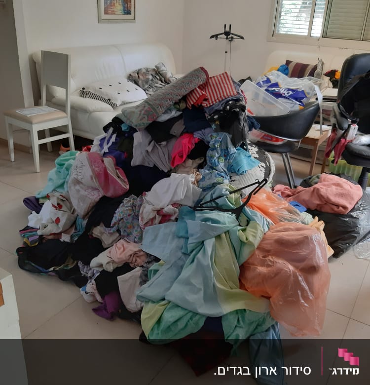 ערימת בגדים צבעונית על הרצפה בחדר מגורים